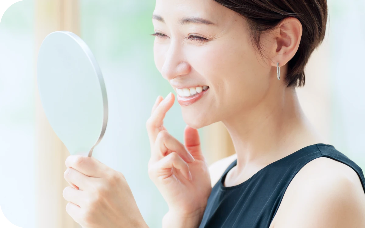 鏡を見て矯正後の歯並びを確認する女性の写真